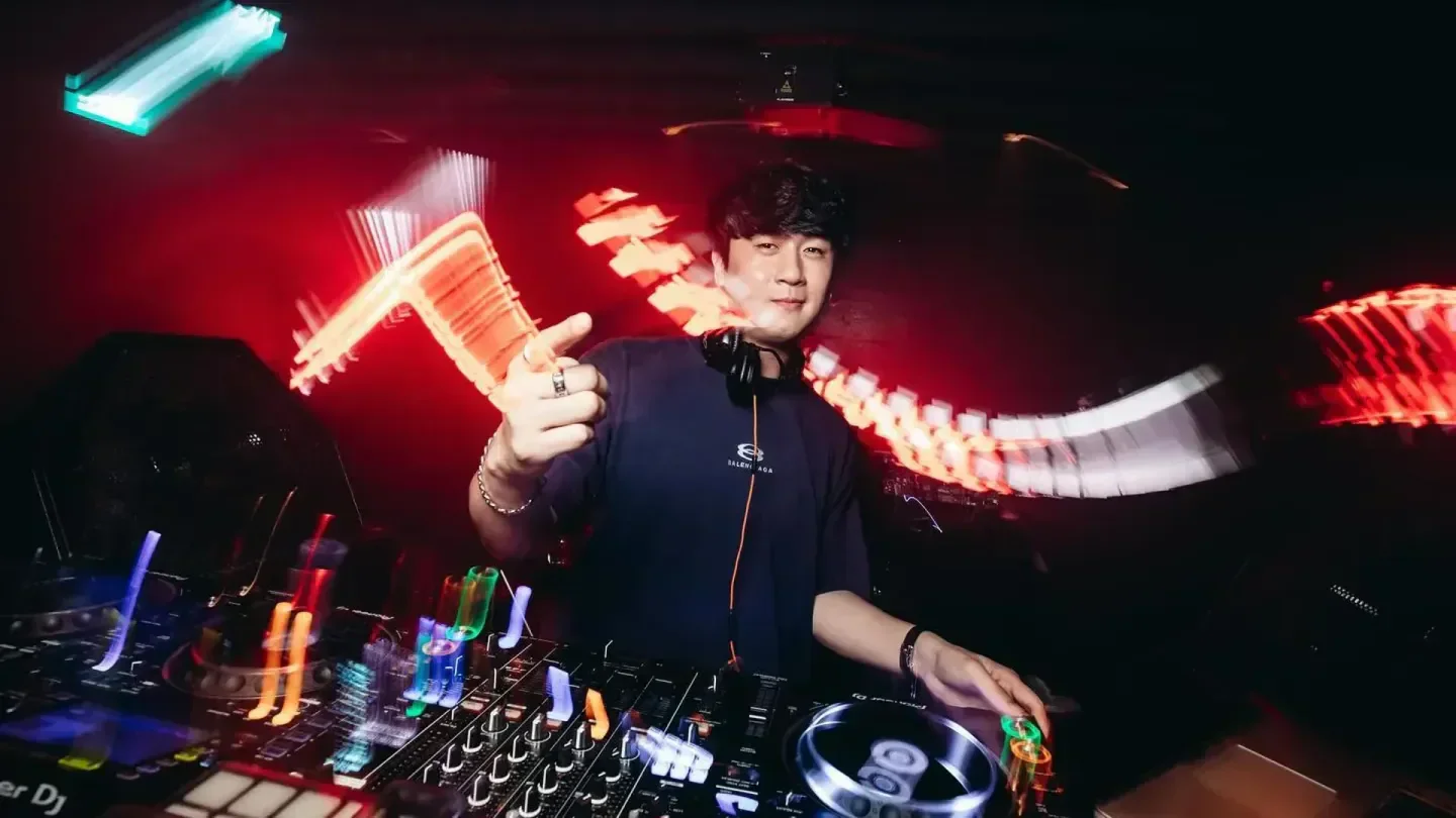 DJ at Capital nightclub in Singapore with neon lights and music mixing console.