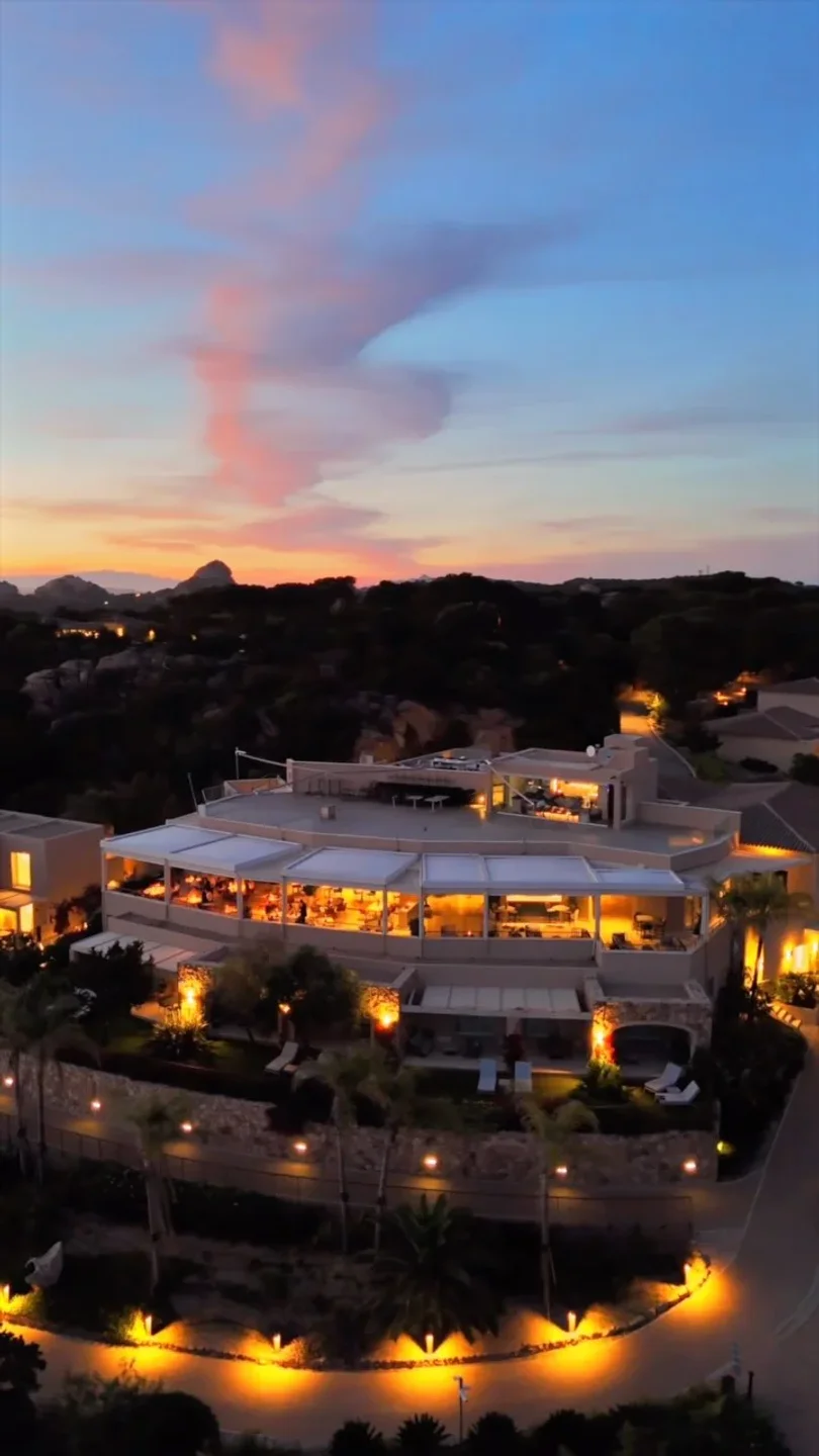 Capogiro restaurant exterior at dusk in Porto Cervo with illuminated dining area and scenic sunset sky.