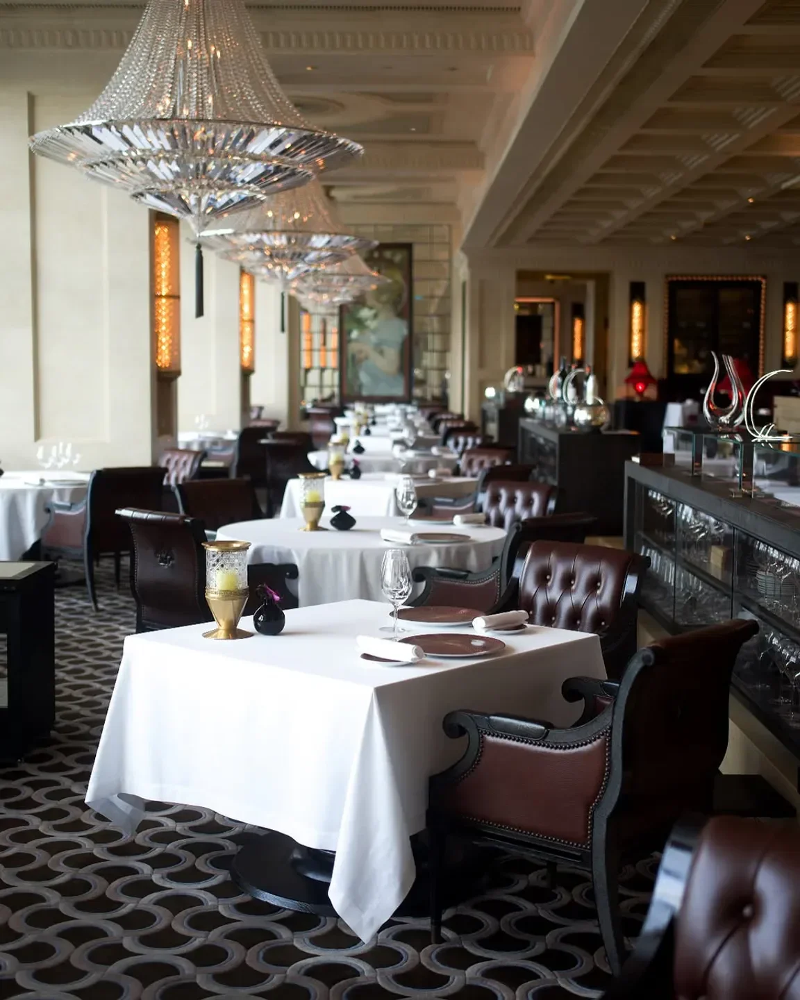 Elegant dining room at Caprice restaurant in Hong Kong, featuring chandeliers and decor.