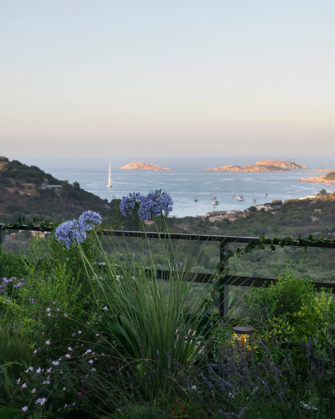 Scenic ocean view from Casa Fiori Chiari restaurant in Porto Cervo with blue flowers and yachts