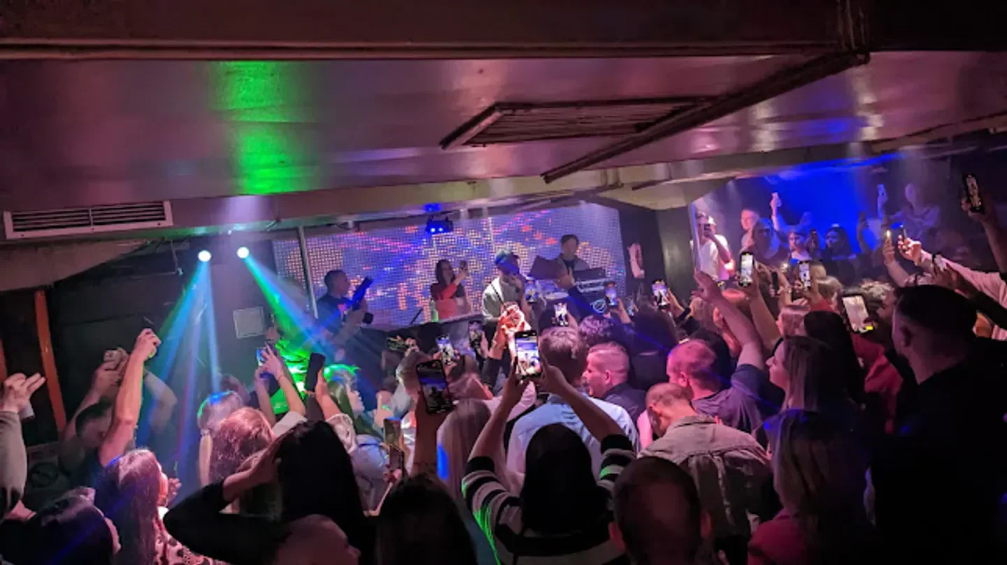 Crowded dance floor at Cave Club & Lounge in Hamburg, with people taking photos.