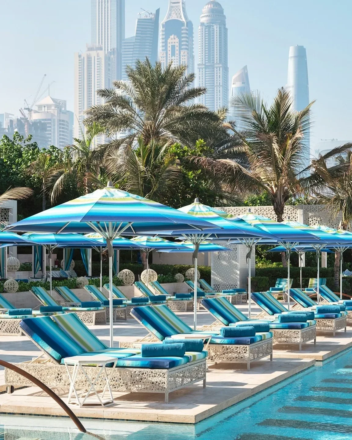 Poolside relaxation at Celebrities by Mauro Colagreco in Dubai with city skyline views.