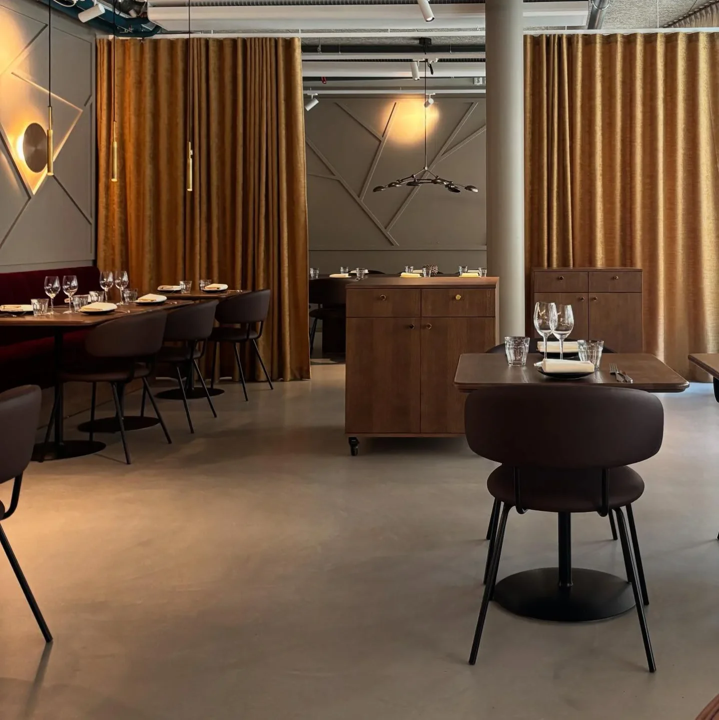 The modern dining room interior of Celeste restaurant features velvet curtains and elegant table settings.