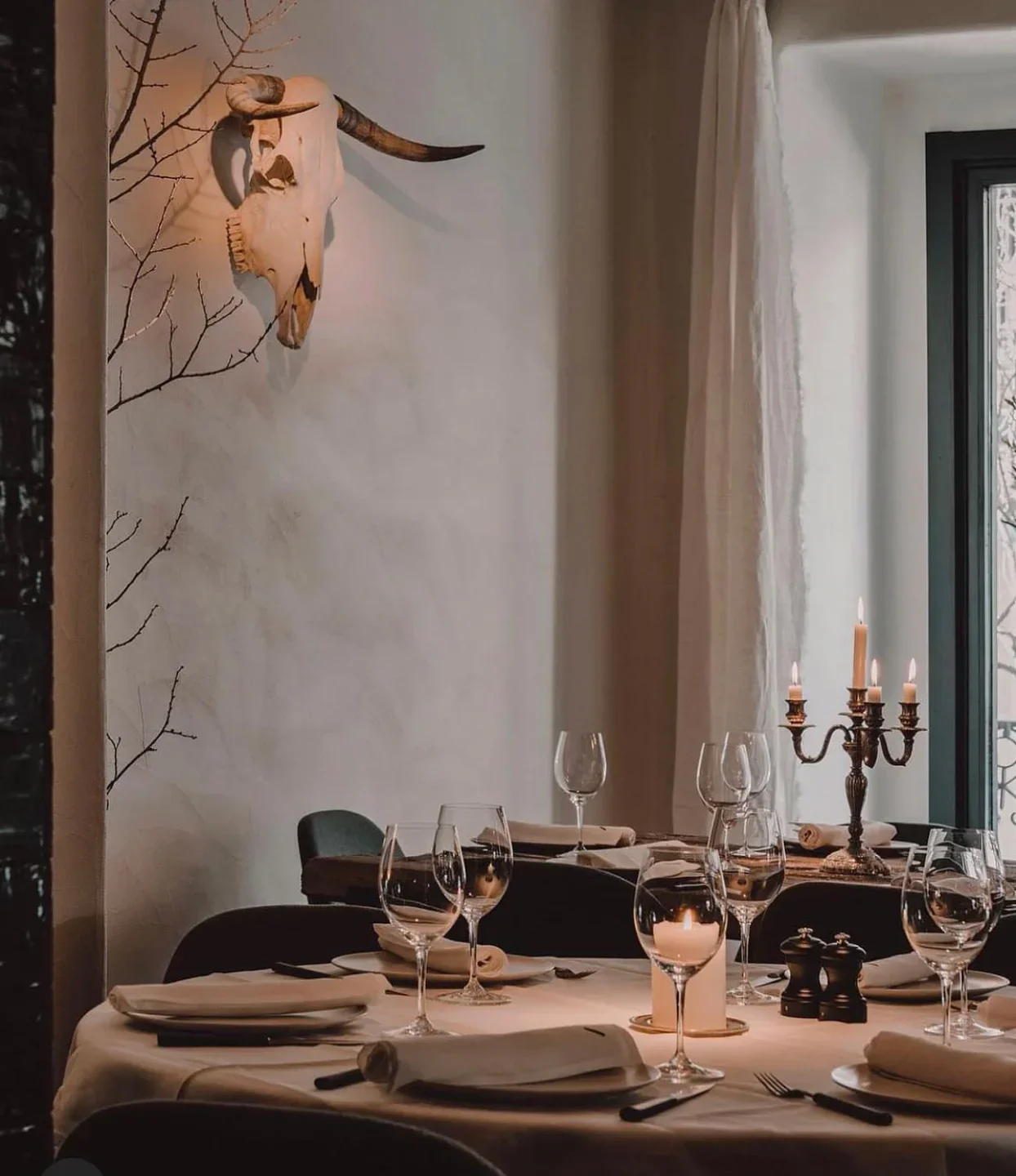 Charrúa restaurant interior featuring a bull skull decor and elegantly set dining tables in the city.