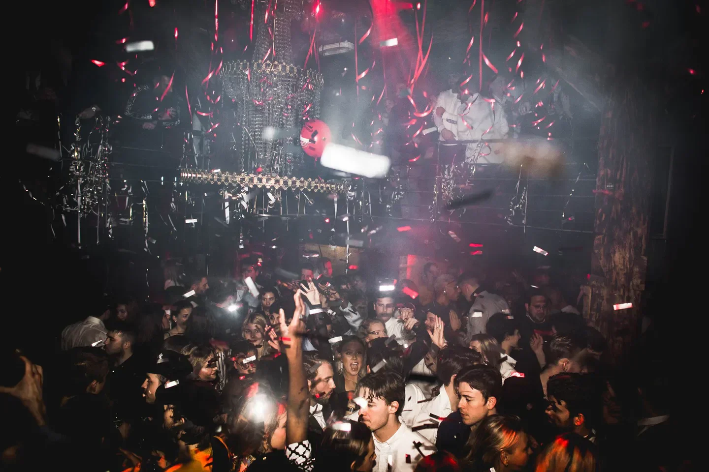 Energetic crowd partying at Chateau Motel nightclub in Copenhagen with confetti and red lights