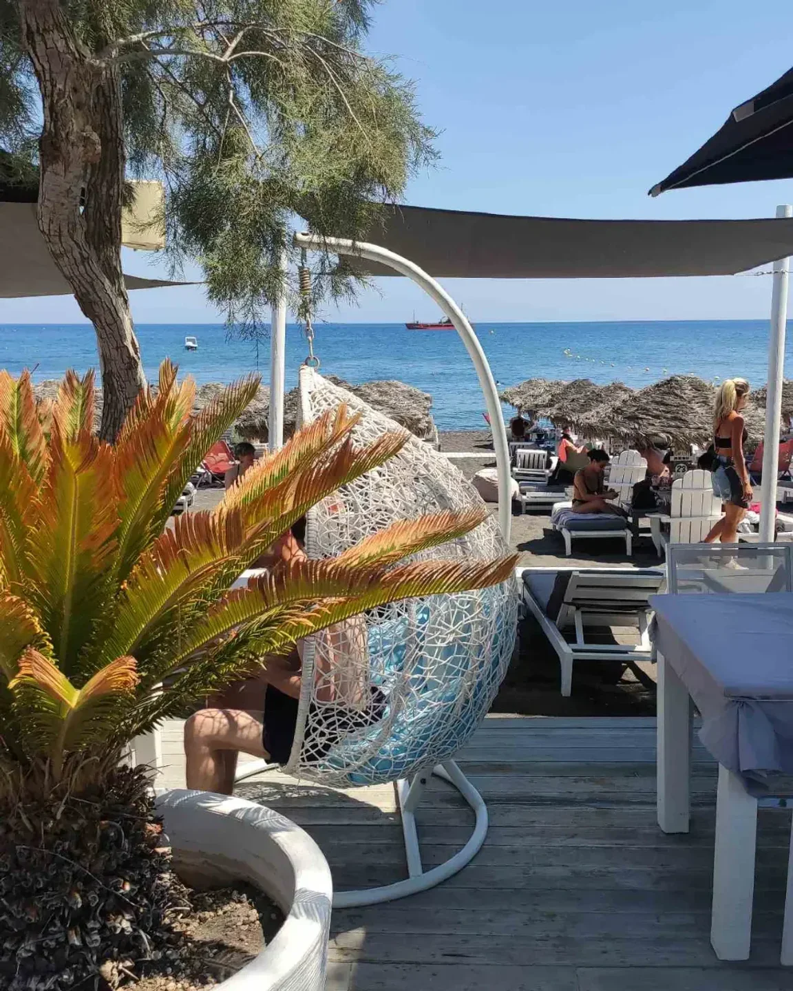 Chilli Beach Bar Santorini offers relaxing beach seating with ocean views and comfortable hanging chairs.