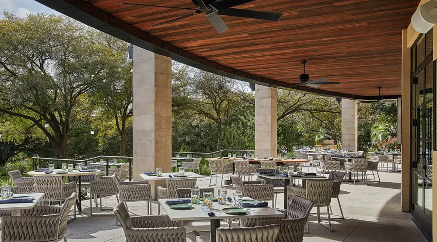 Outdoor dining at Ciclo in Austin, featuring tables and a view of surrounding trees.