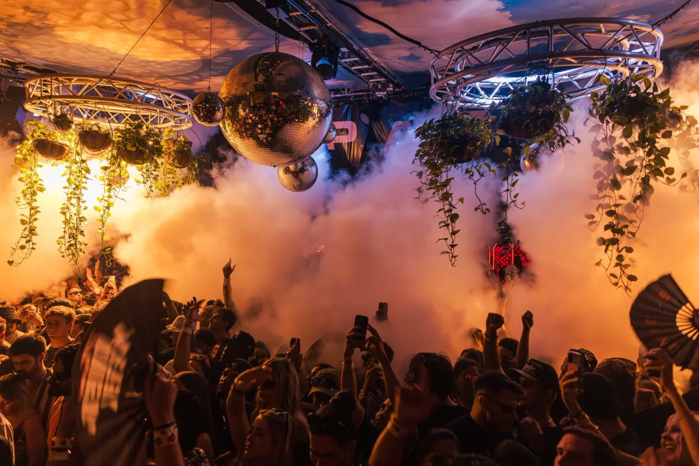 Lush hanging plants and disco balls create ambiance at Club Space Miami's energetic nightclub event.