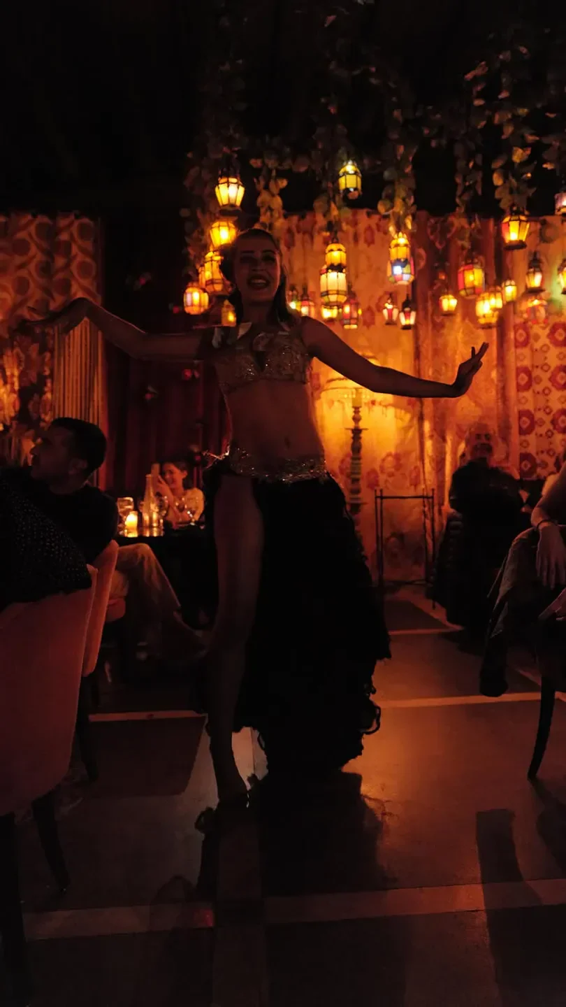 Belly dancer performing at Comptoir Darna in Marrakech, with vibrant lanterns and decor.
