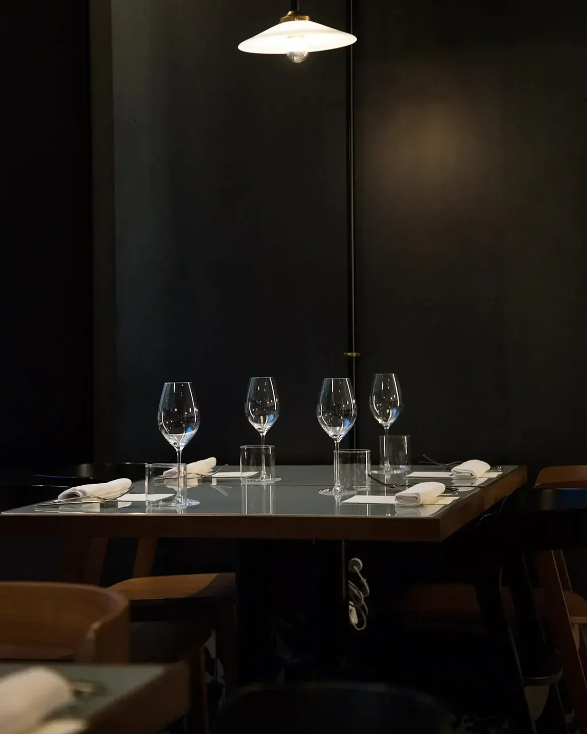 Elegant dining table set at Confine - Pizza E Cantina in Milan, Italy, with wine glasses.