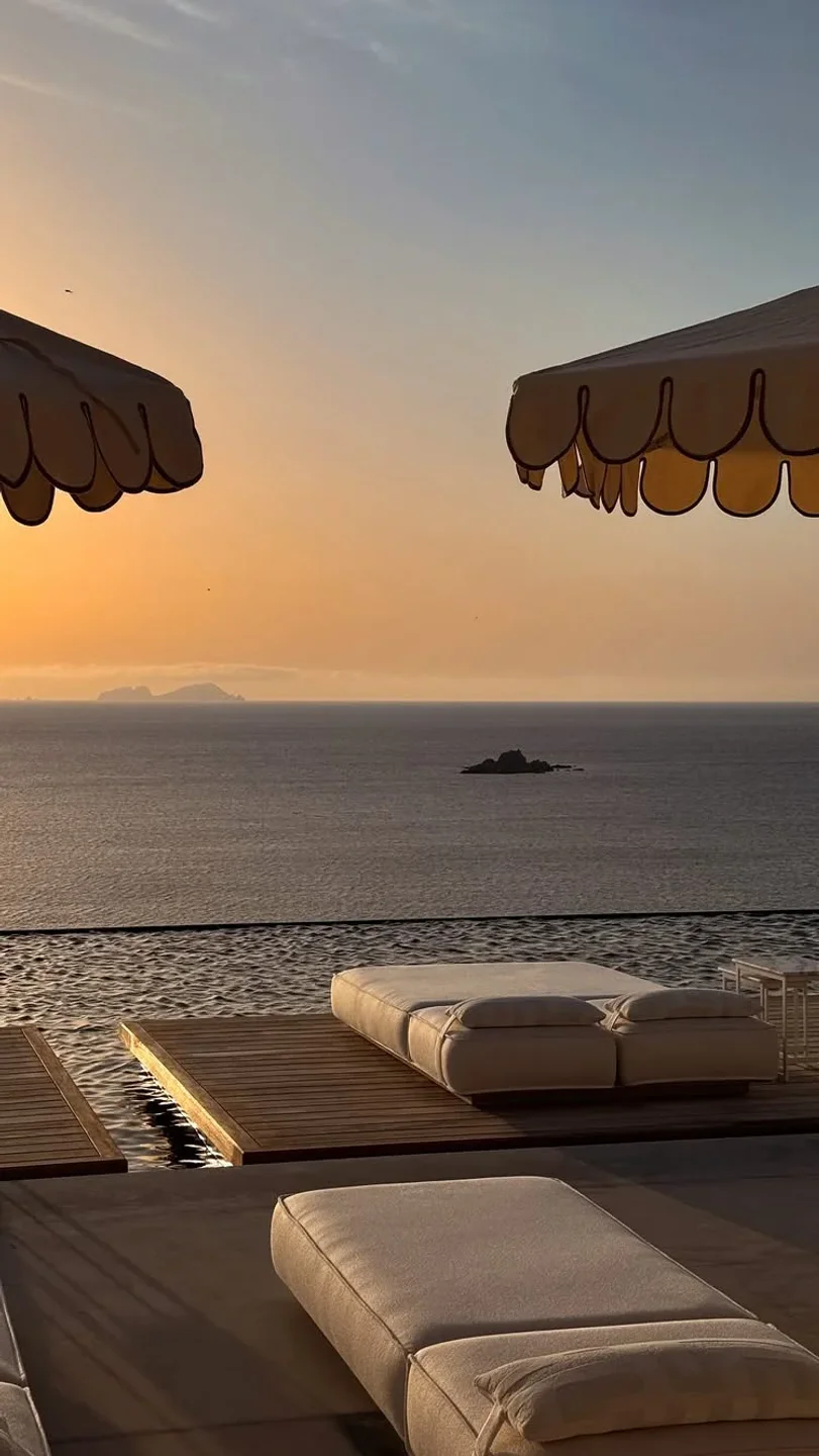 Corbu Mykonos seaside lounge area with sunbeds and umbrellas at sunset