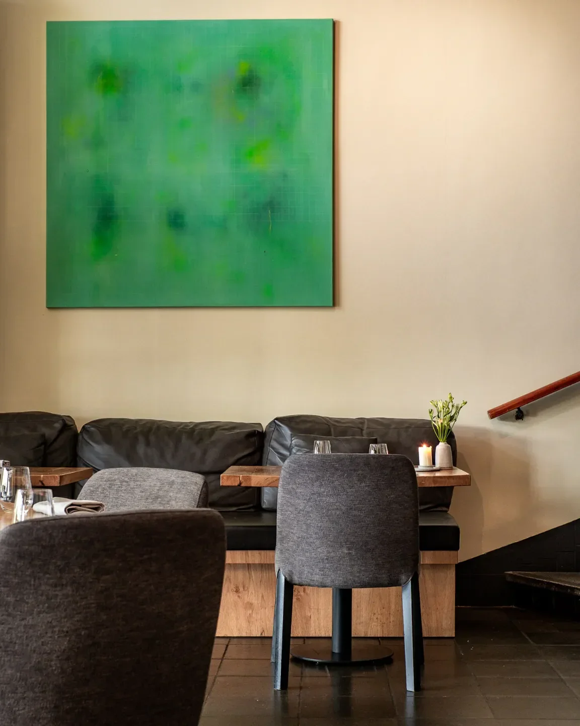 Interior of Coulisse restaurant in Amsterdam. Featuring a large green painting and stylish seating.