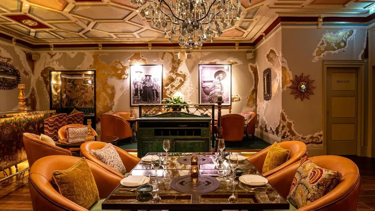 Elegant dining area at COYA Doha, featuring stylish decor and a shimmering chandelier.