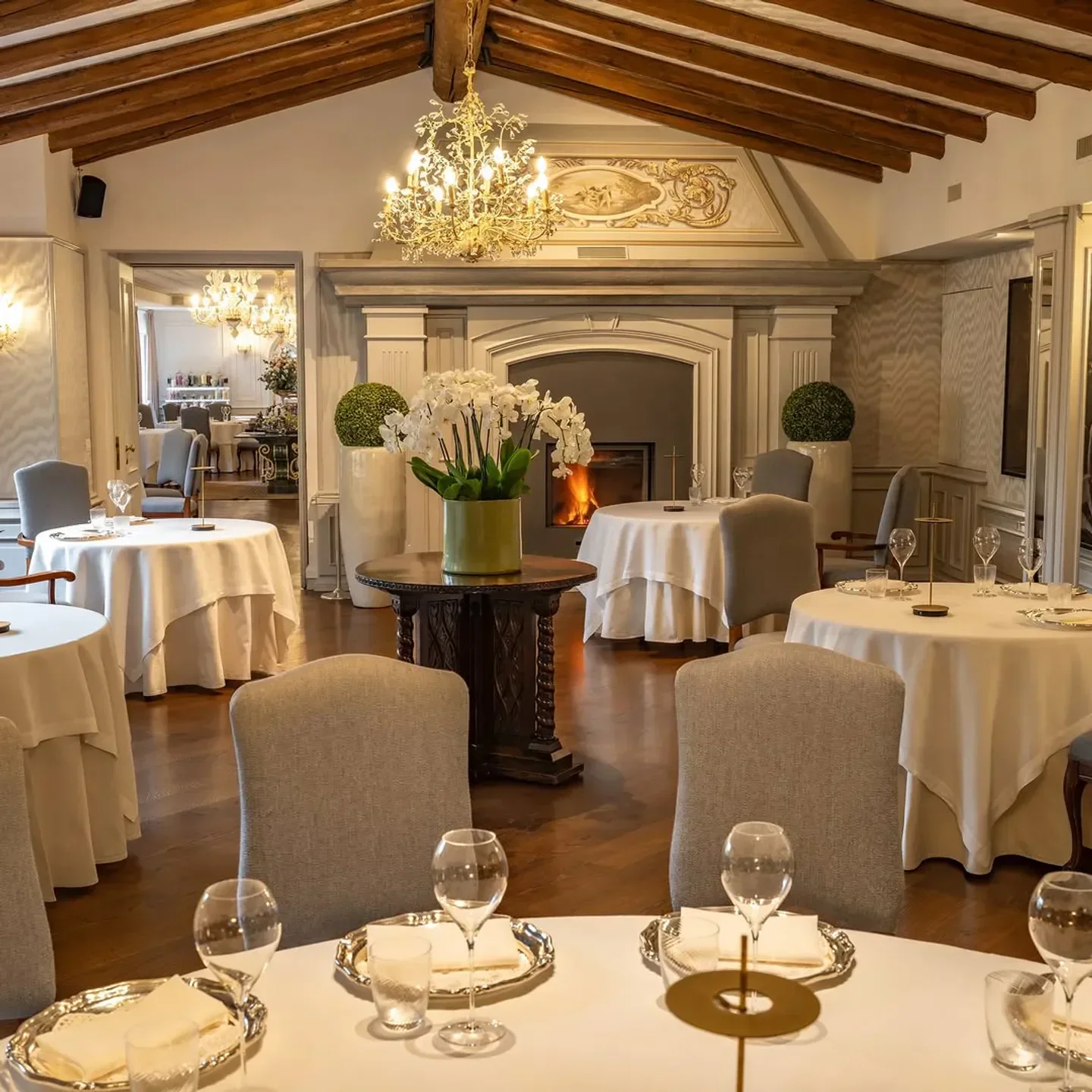 Elegant dining room at Da Vittorio Shanghai, with tables set by a fireplace.