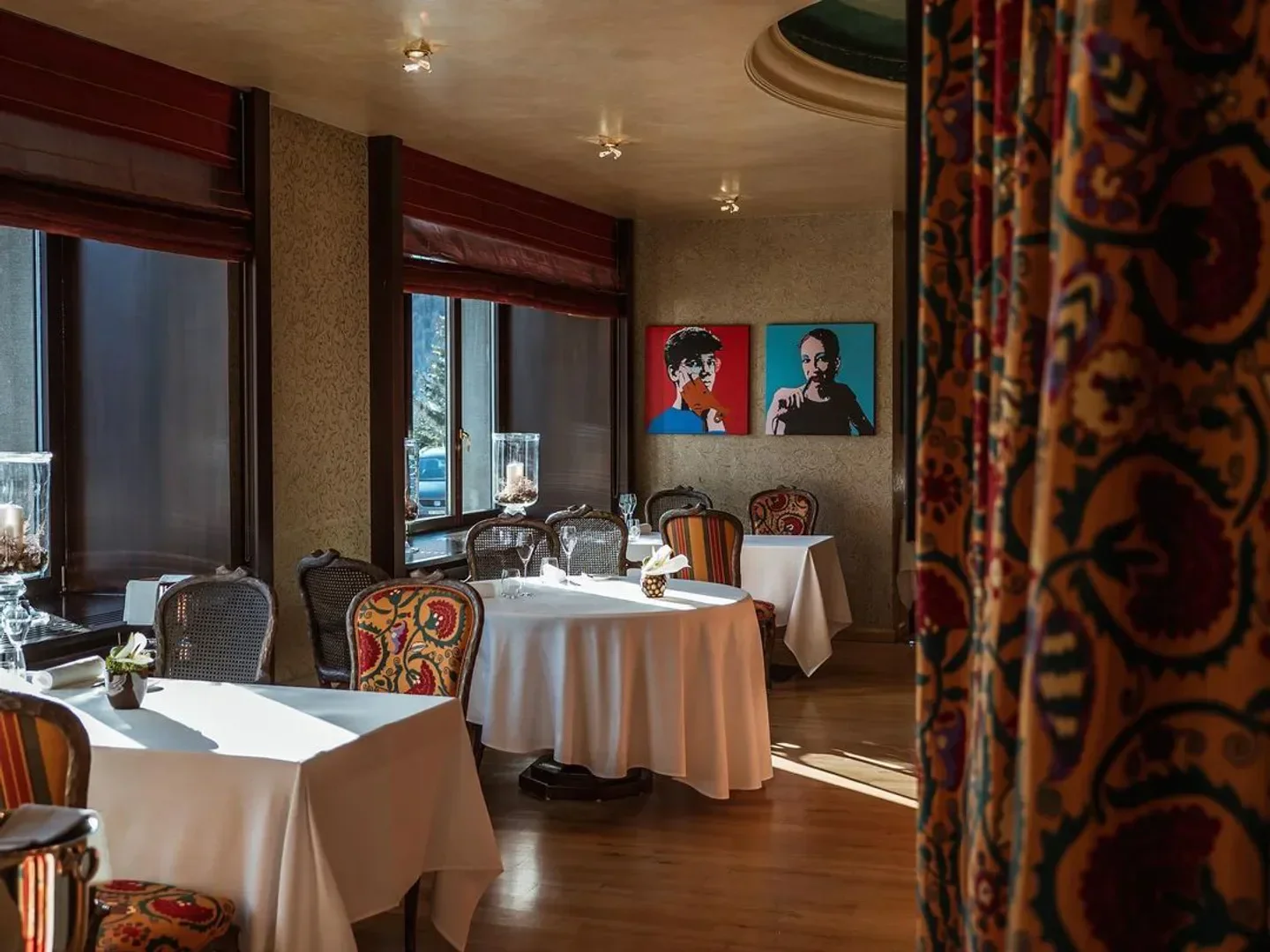 Elegant interior of Da Vittorio restaurant in St. Moritz with art and floral chairs