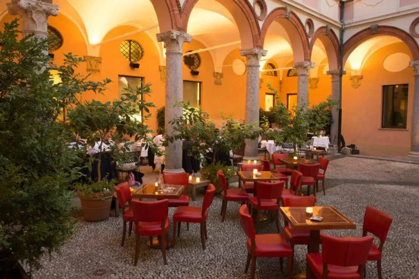 Outdoor dining at Dal Bolognese Milano in Milan, showcasing red chairs and ambiance.