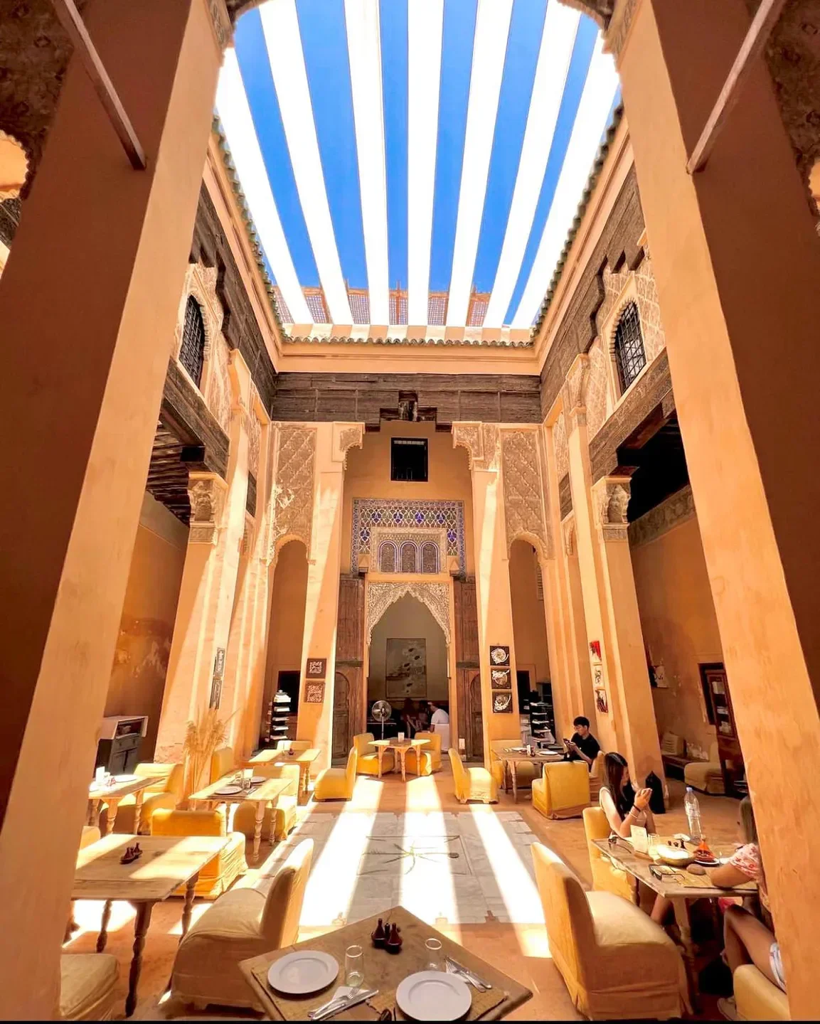 Interior dining at Dar Zellij restaurant in Marrakech, with open ceiling and dining tables.