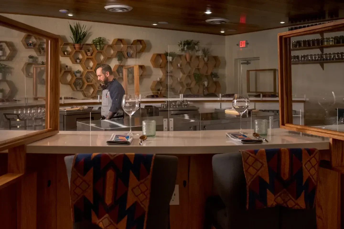 Interior view of Degust restaurant in Houston, with bar seating and chef in background.