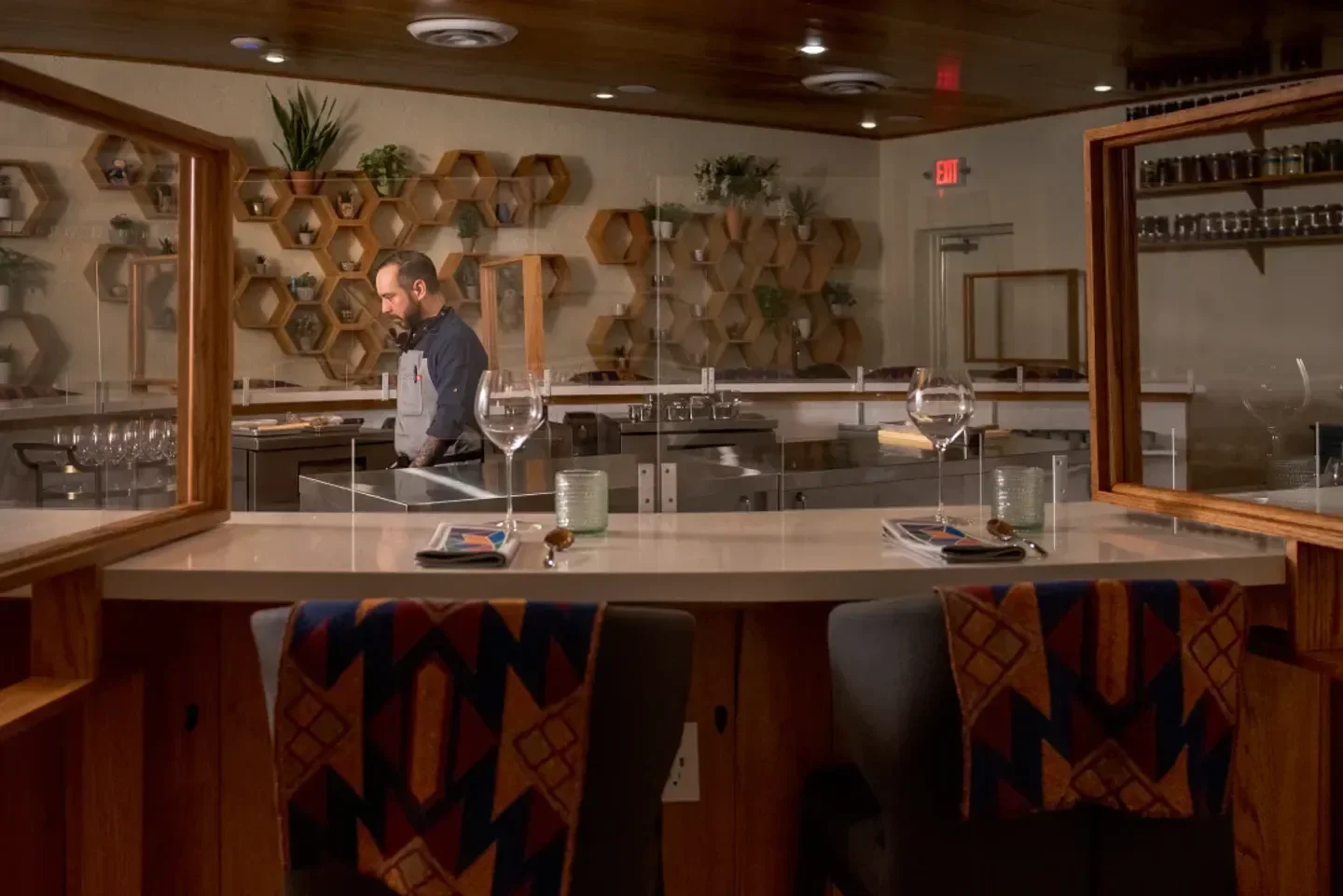 Interior view of Degust restaurant in Houston, with bar seating and chef in background.