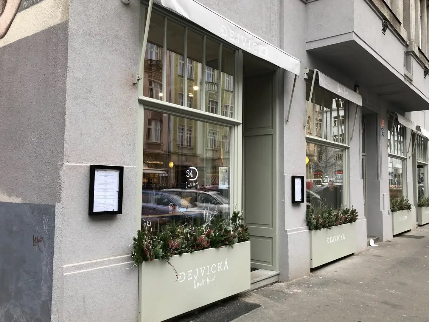 Exterior view of Dejvická 34 restaurant in Prague, with facade and menu displayed.