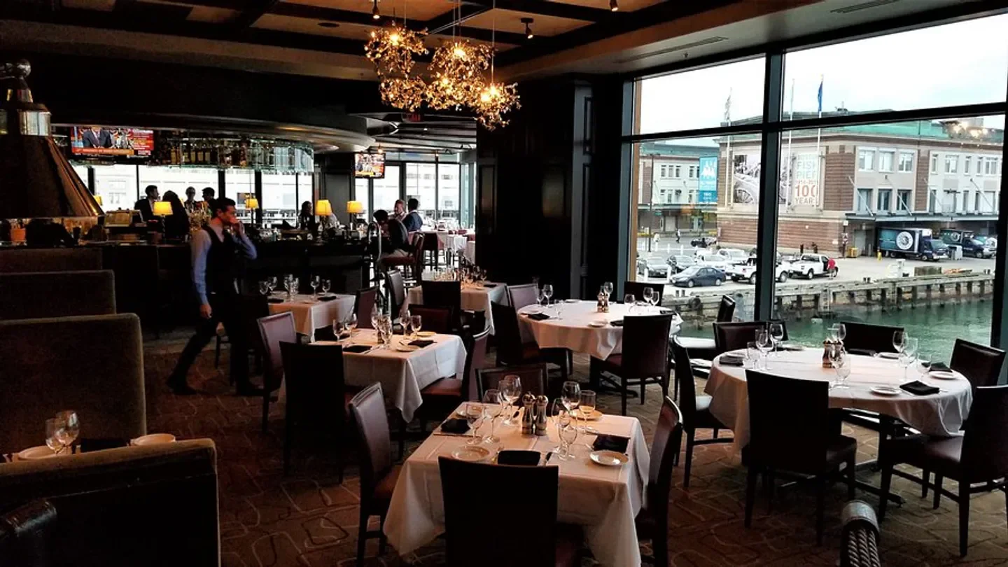 Interior of Del Frisco's Double Eagle Steakhouse in Boston, with waterfront views and dining tables.