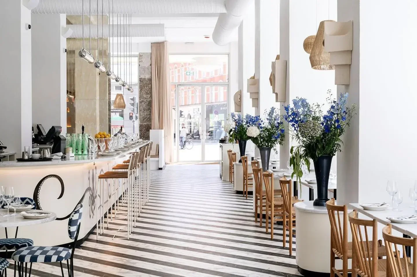 Stylish interior of Delphine restaurant in Copenhagen, with floral arrangements and striped floors.