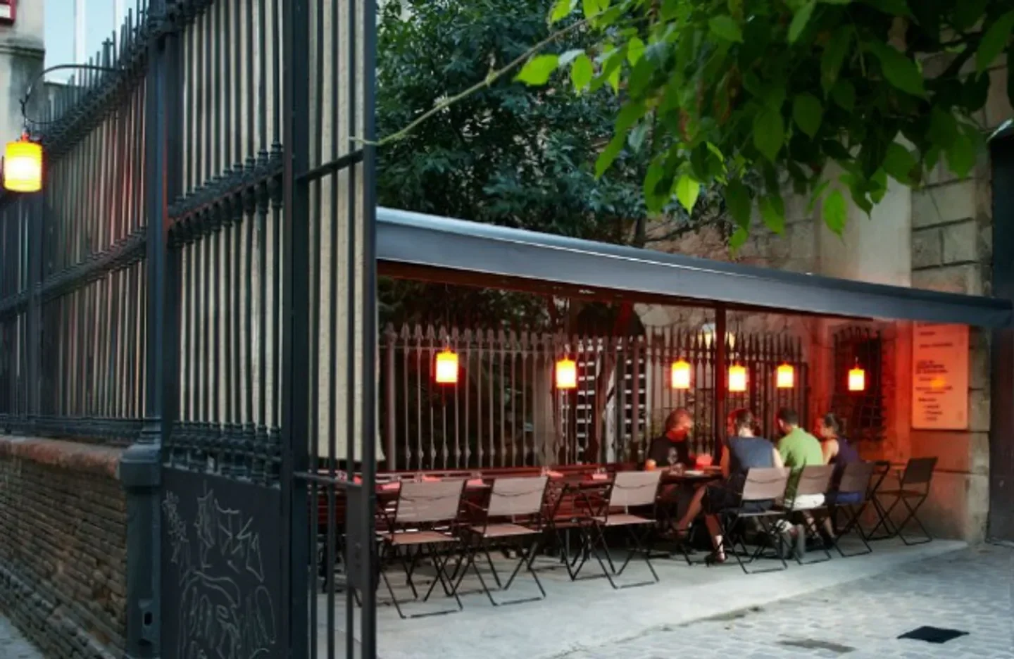 Outdoor dining at Dos Palillos in Barcelona, with cozy lights and wrought-iron gate.