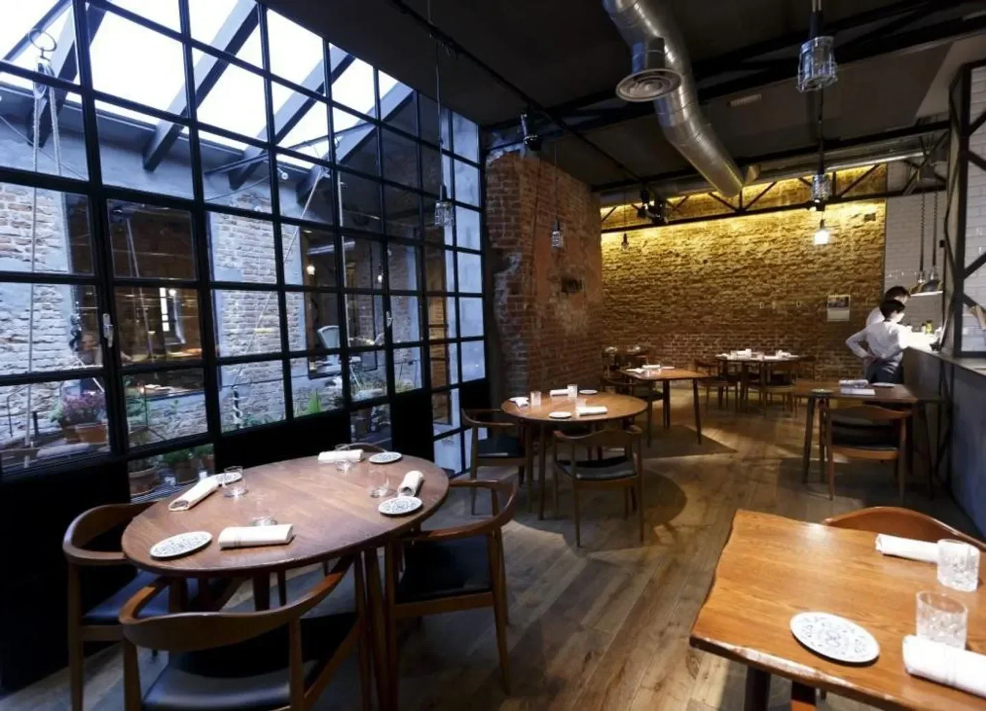 Cozy dining room at DSTAgE restaurant in Madrid, with brick walls and wooden tables
