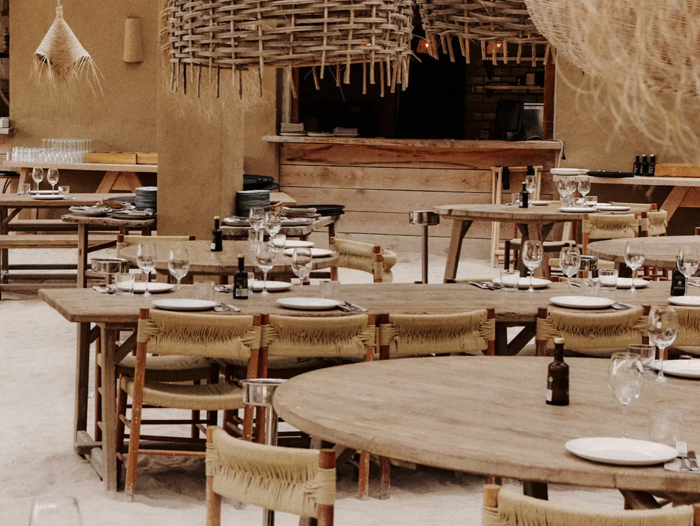 El Silencio Ibiza beach club interior with rustic wooden tables and chairs set for dining