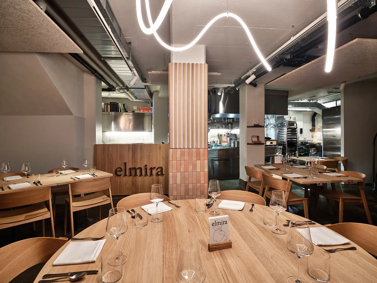 Modern interior of elmira restaurant in Zurich, featuring elegant wooden tables and stylish decor.