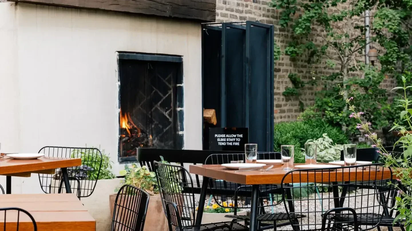 Cozy outdoor dining space at Elske restaurant in Chicago, with fireplace and tables.