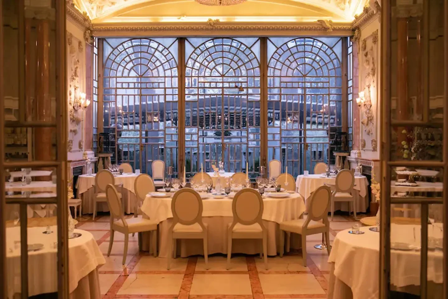 Elegant dining room at Enoteca la Torre, Rome, featuring round tables and large windows.