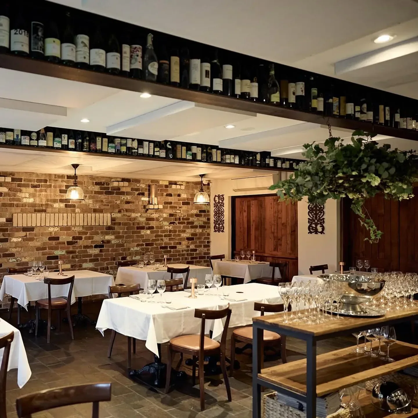 Interior of Entrata restaurant in Sydney, featuring tables, wine bottles, and rustic brick wall.