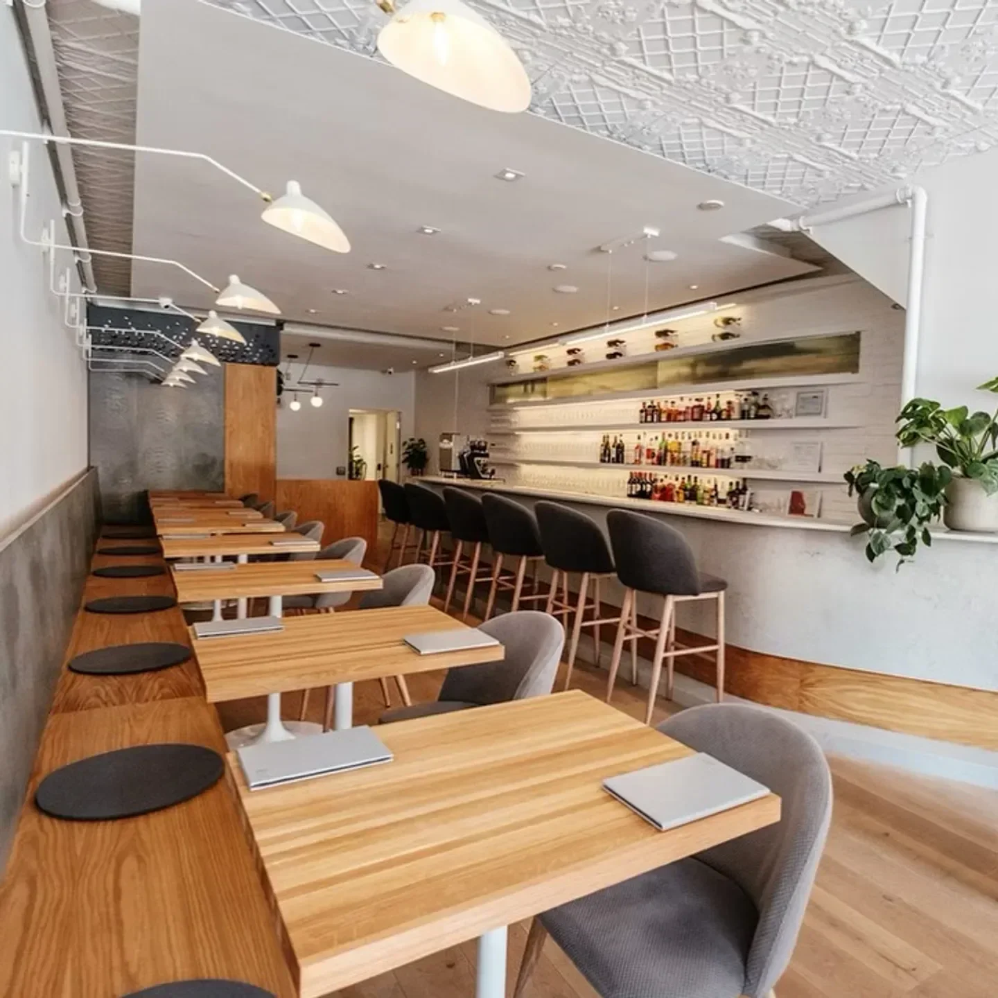 Interior of ēst Restaurant in Toronto featuring stylish tables and bar seating.