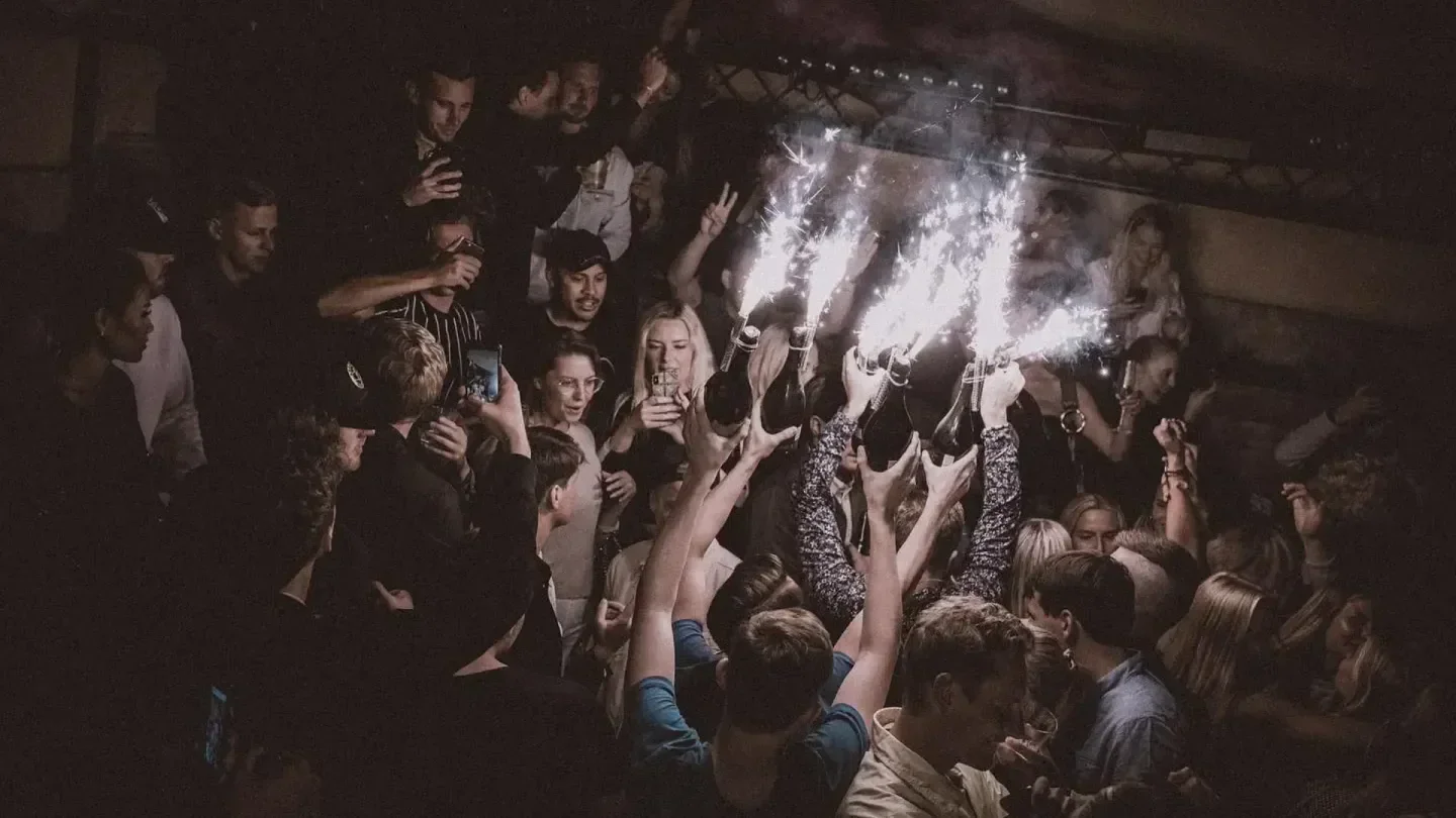 Party at F12 Terrassen nightclub in Stockholm with sparklers and raised bottles