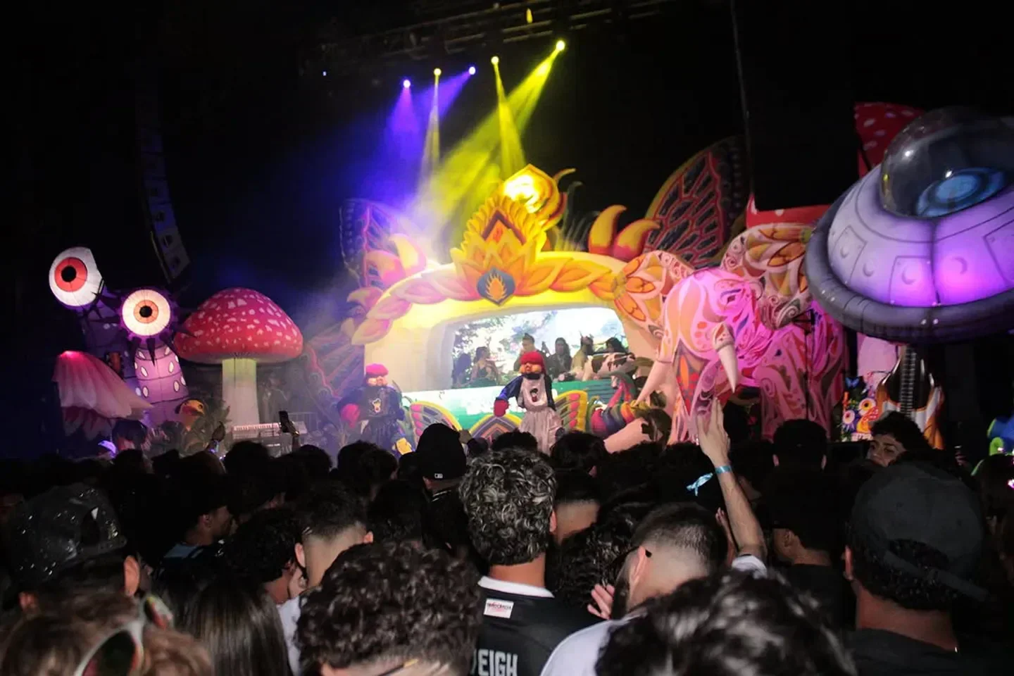 Colorful crowd at Favela Encantada nightclub in Boston enjoying a vibrant party with stage decor.