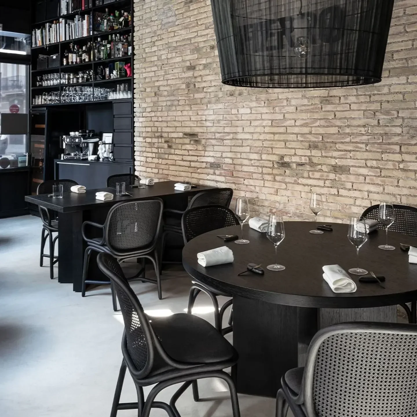 Interior of Fierro restaurant in Valencia with tables, chairs, and brick wall.