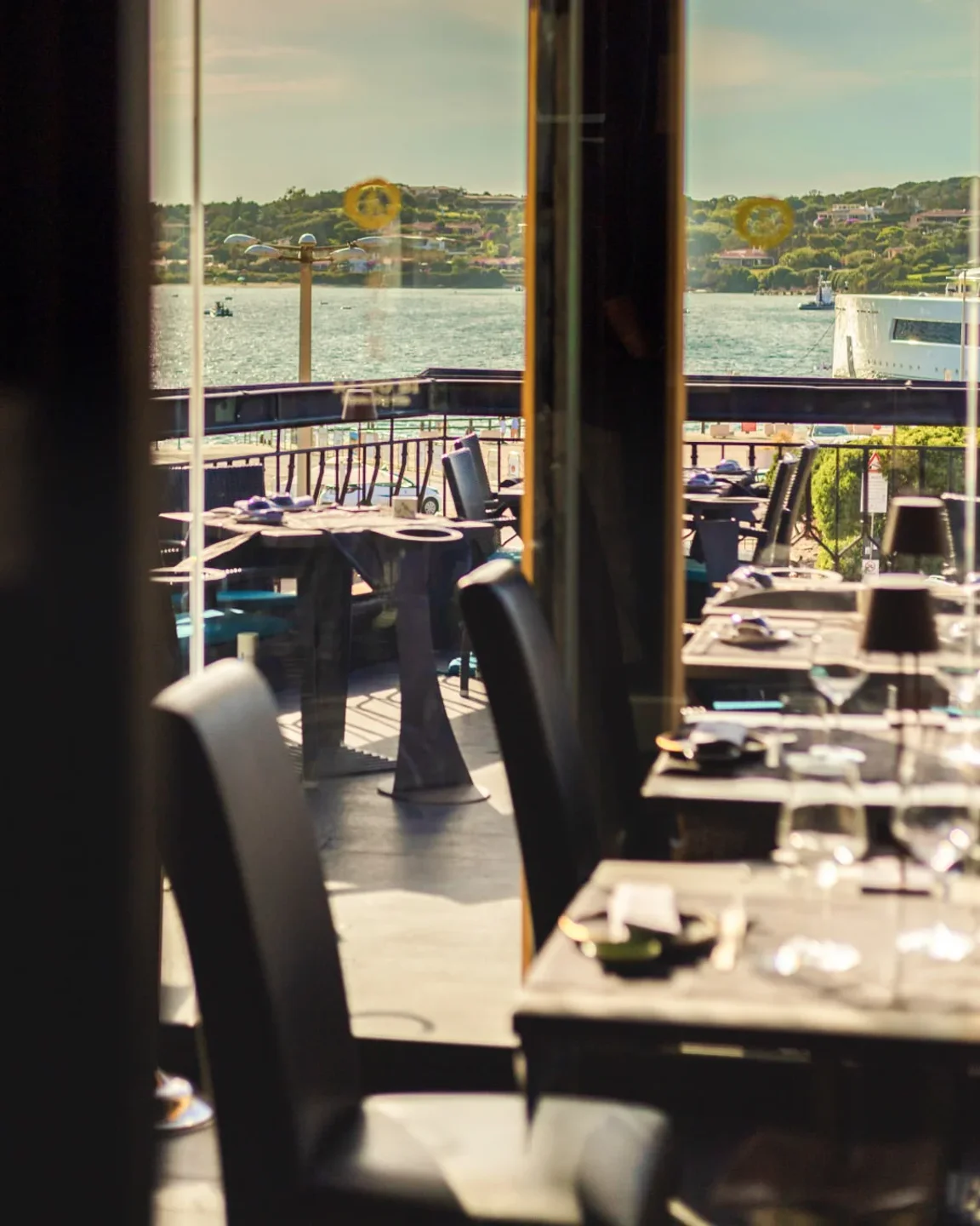 Outdoor dining tables at Finger's restaurant in Porto Cervo with a view of the sea and yachts.