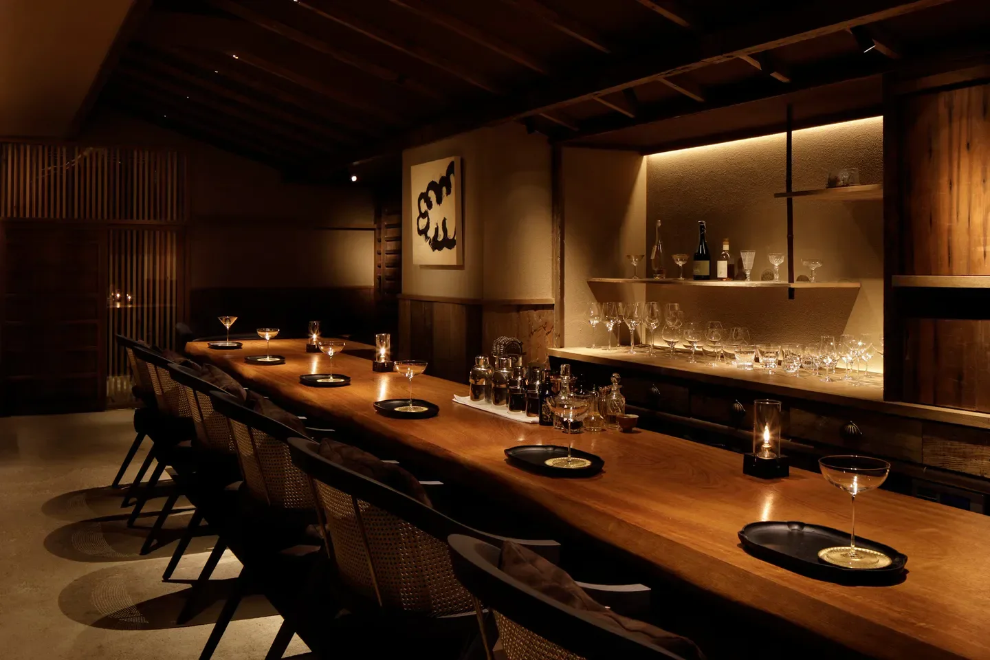 Cozy bar interior at FOLKLORE restaurant in Tokyo, featuring a long wooden counter and cocktails.