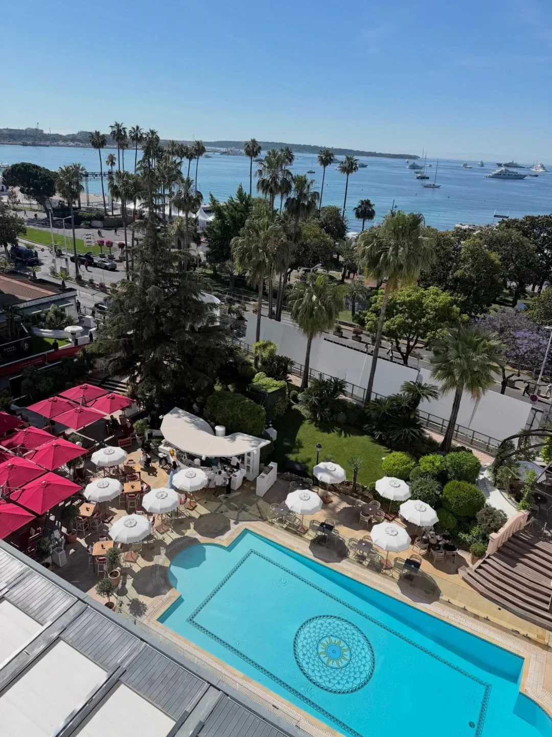 Fouquet's Cannes boasts a stunning poolside terrace with red umbrellas and views of yachts in the bay.