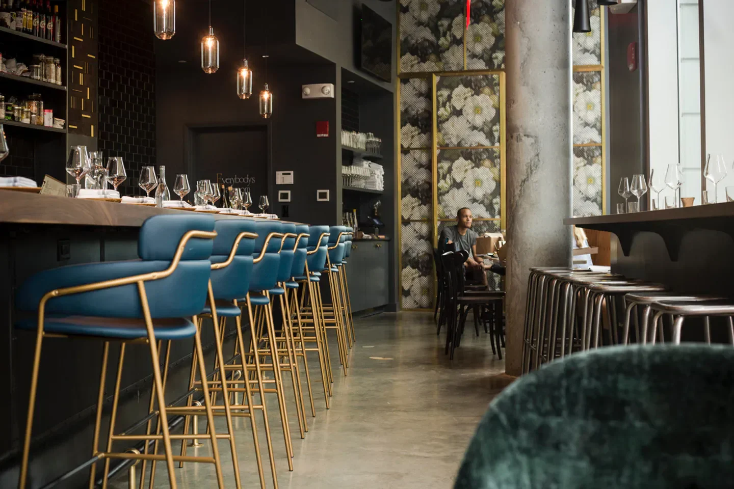 Interior view of Fox & the Knife restaurant in Boston, with blue bar stools.