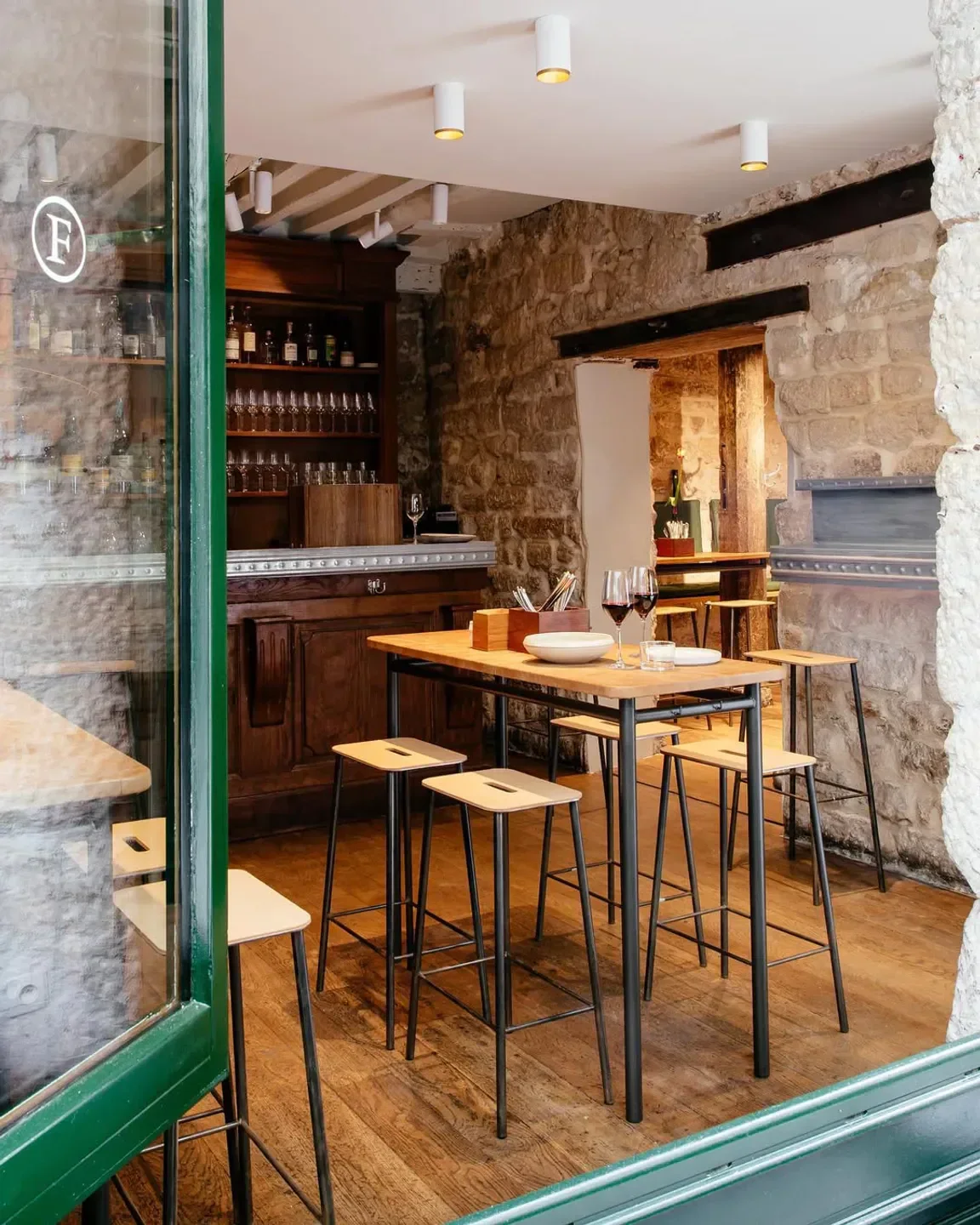 Cozy interior of Frenchie restaurant in Paris, featuring stone walls and wooden tables