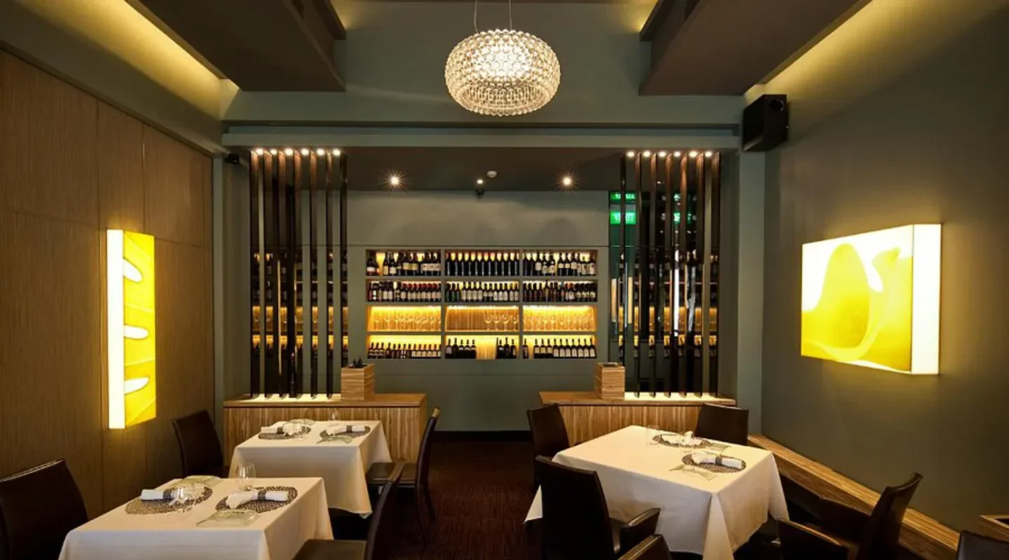 Elegant interior of Garibaldi restaurant in Singapore, featuring wine display and dining tables.