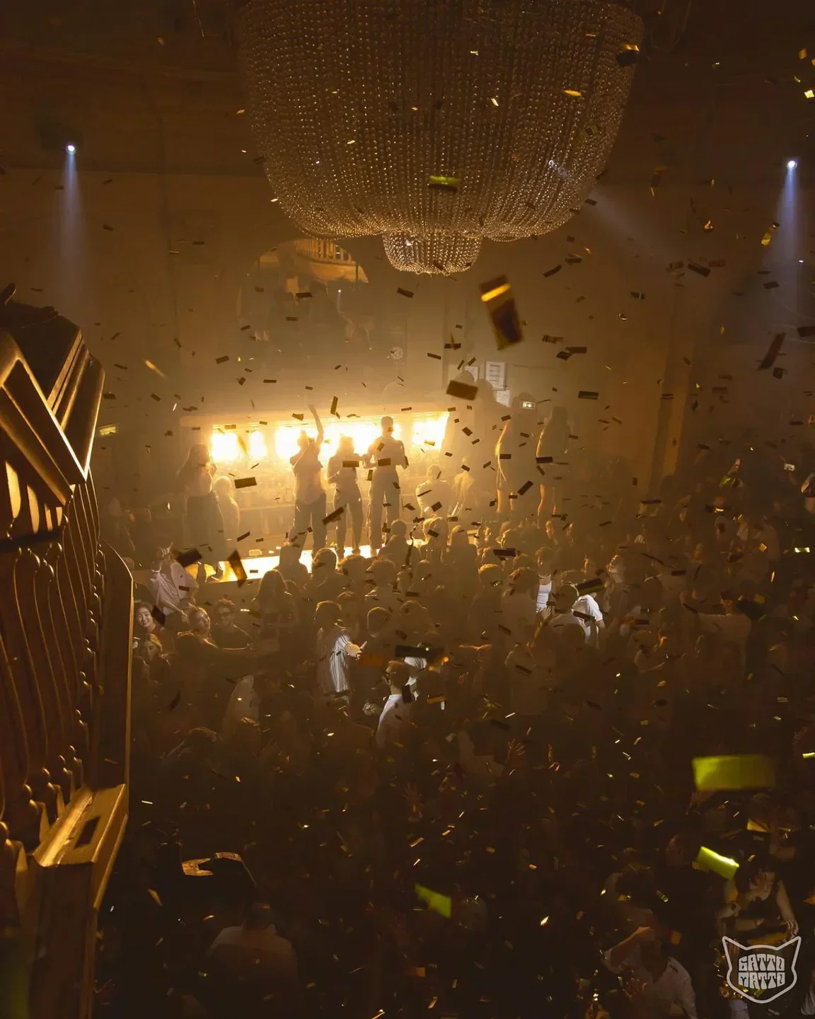 Energetic party scene at Gattopardo nightclub in Milan with confetti and chandelier.