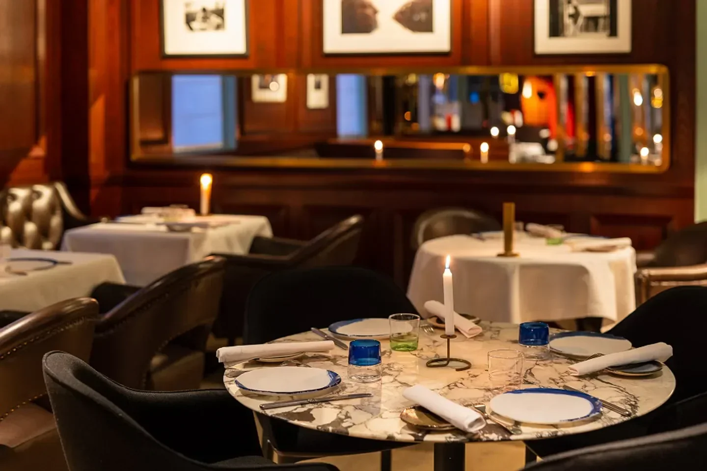 Cozy dining room with tables set at Gaya restaurant in Paris, featuring candle light.