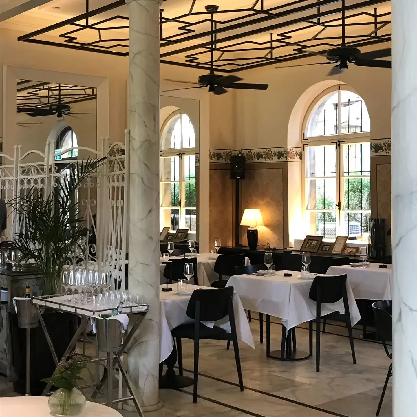 Elegant interior of George and John Restaurant in Tel Aviv, featuring marble columns and arched windows.