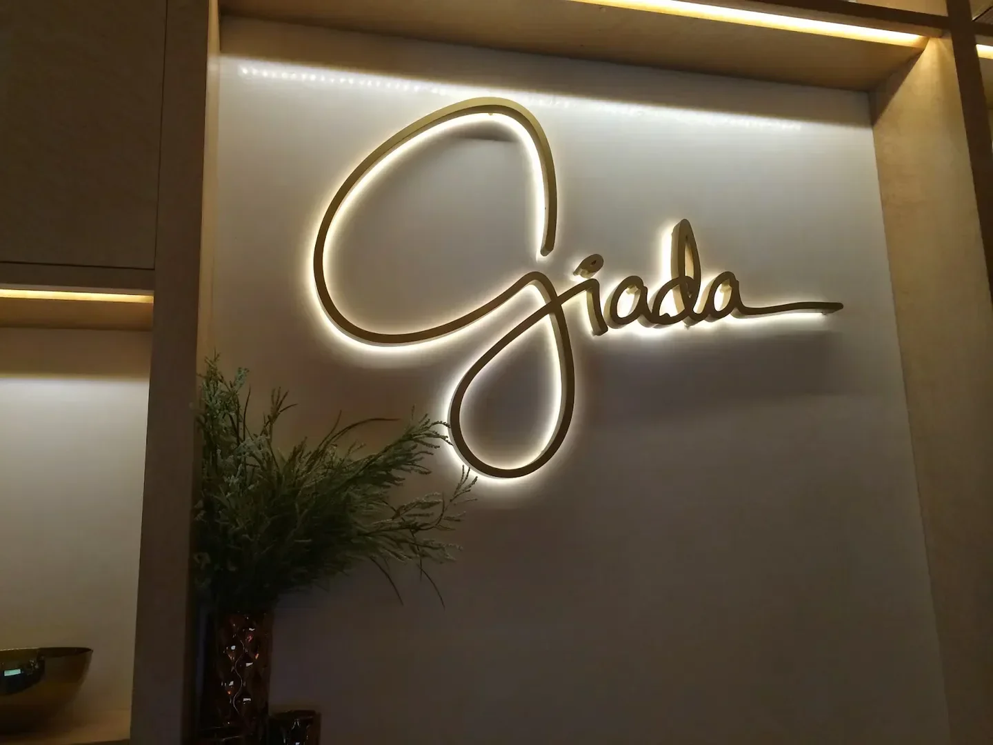 Giada Las Vegas restaurant logo on a wall with elegant lighting and floral decor.