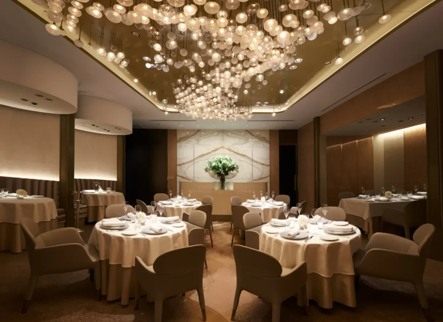 Elegant dining room interior at Ginza L'ecrin in Tokyo with unique light fixture.
