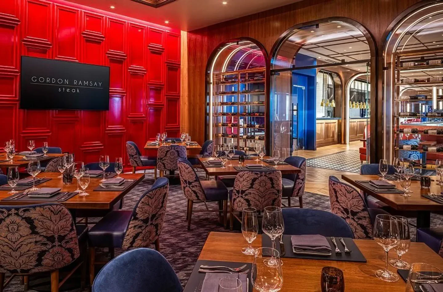 Interior of Gordon Ramsay Steak - Las Vegas, featuring stylish dining area with red wall