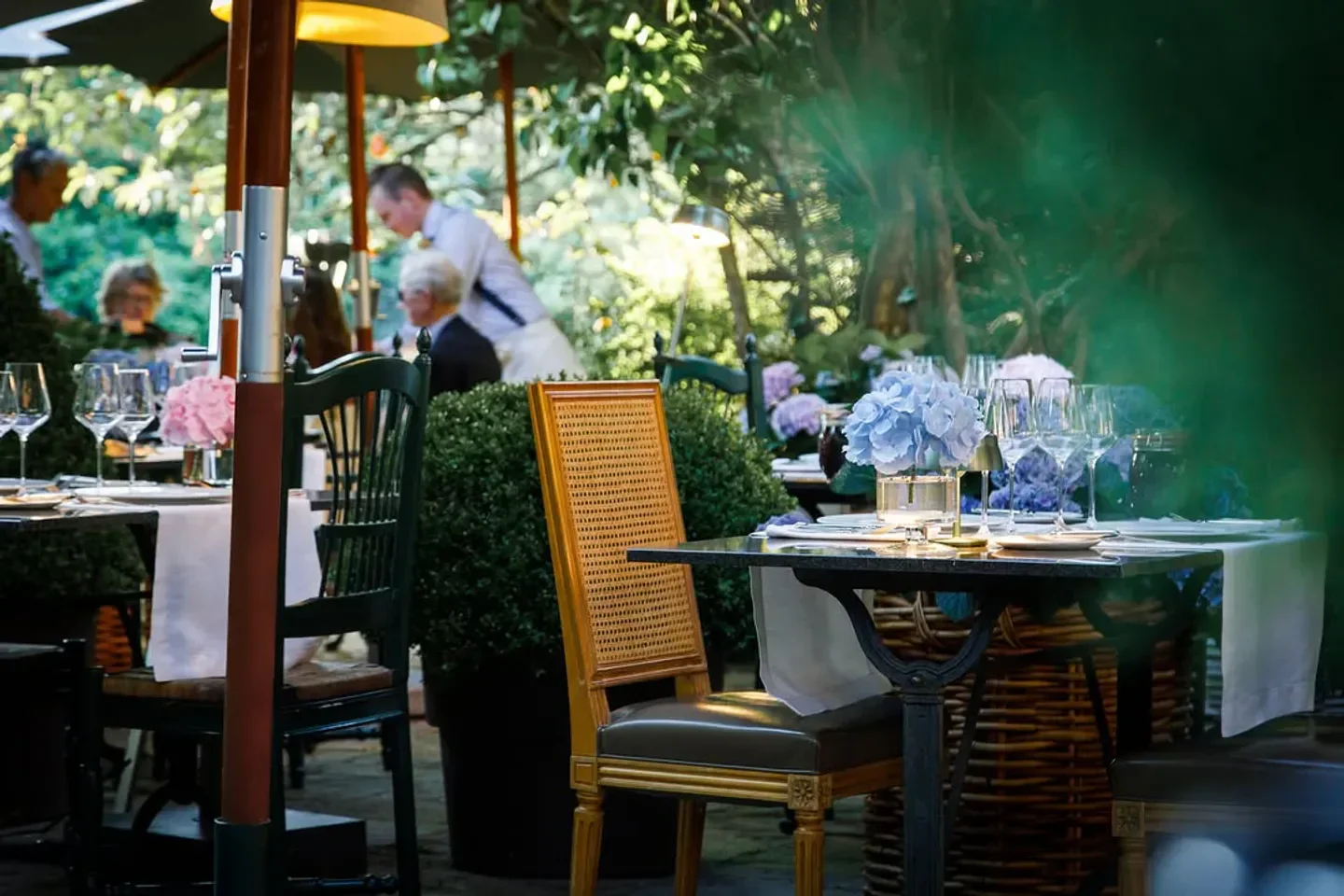 Outdoor dining at Guillou Campagne restaurant in Luxembourg with floral table settings.